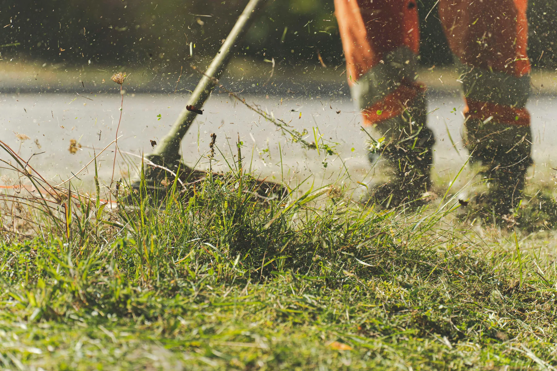 Landscape worker using a string trimmer along a grass edge